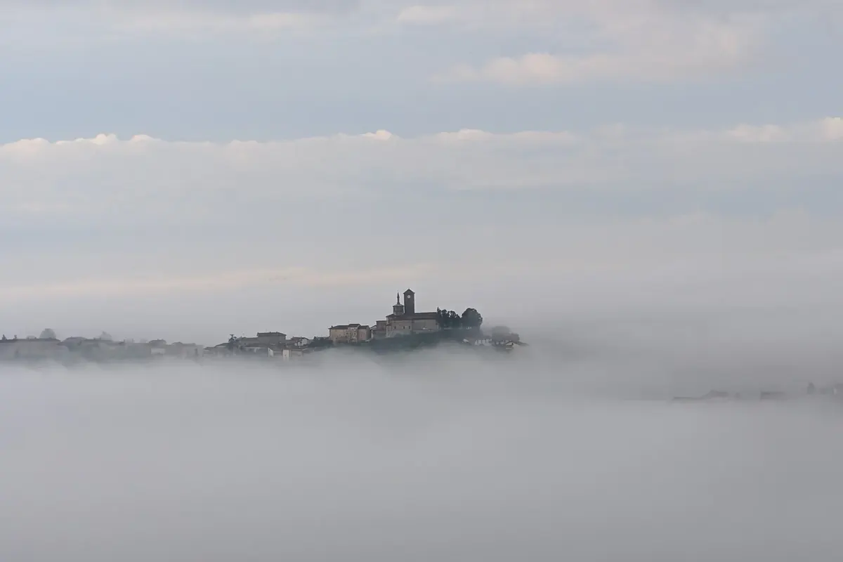 Un borgo del Monferrato che emerge dalla nebbia del mattino